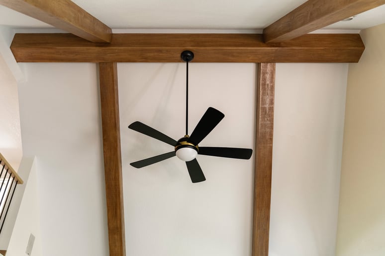 Vaulted ceiling with exposed wooden beams and a black ceiling fan in remodeled home in Des Moines