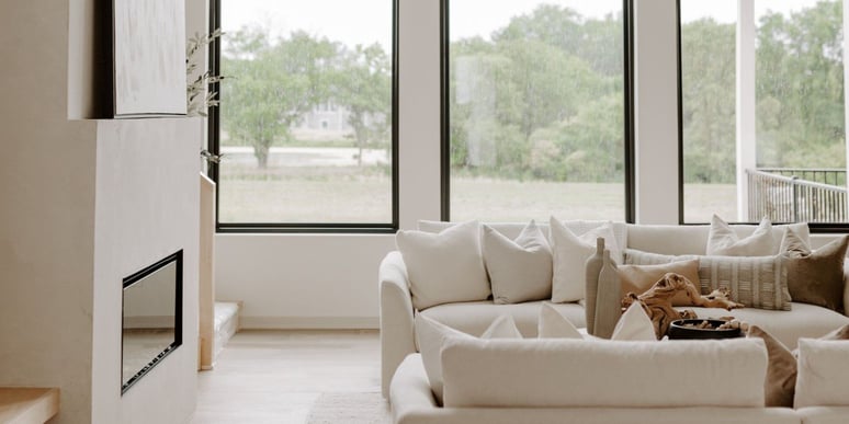 Cozy, minimalist black and white living room with black windows and a large white couch