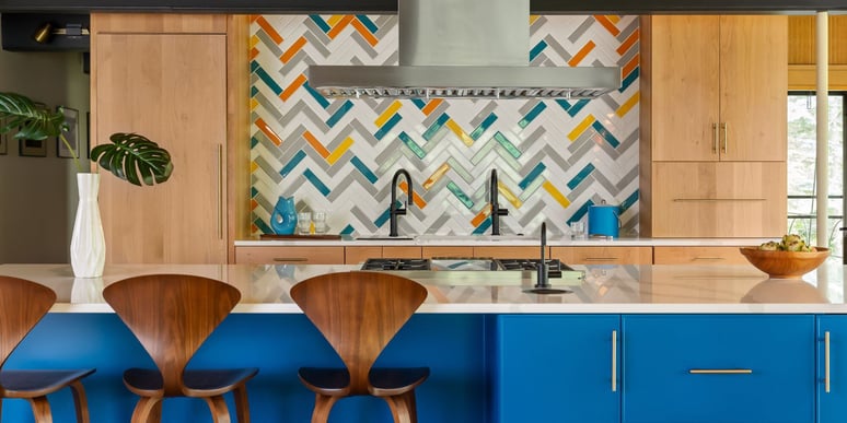 Custom kitchen remodel with bright blue cabinets on kitchen island and statement herringbone backsplash