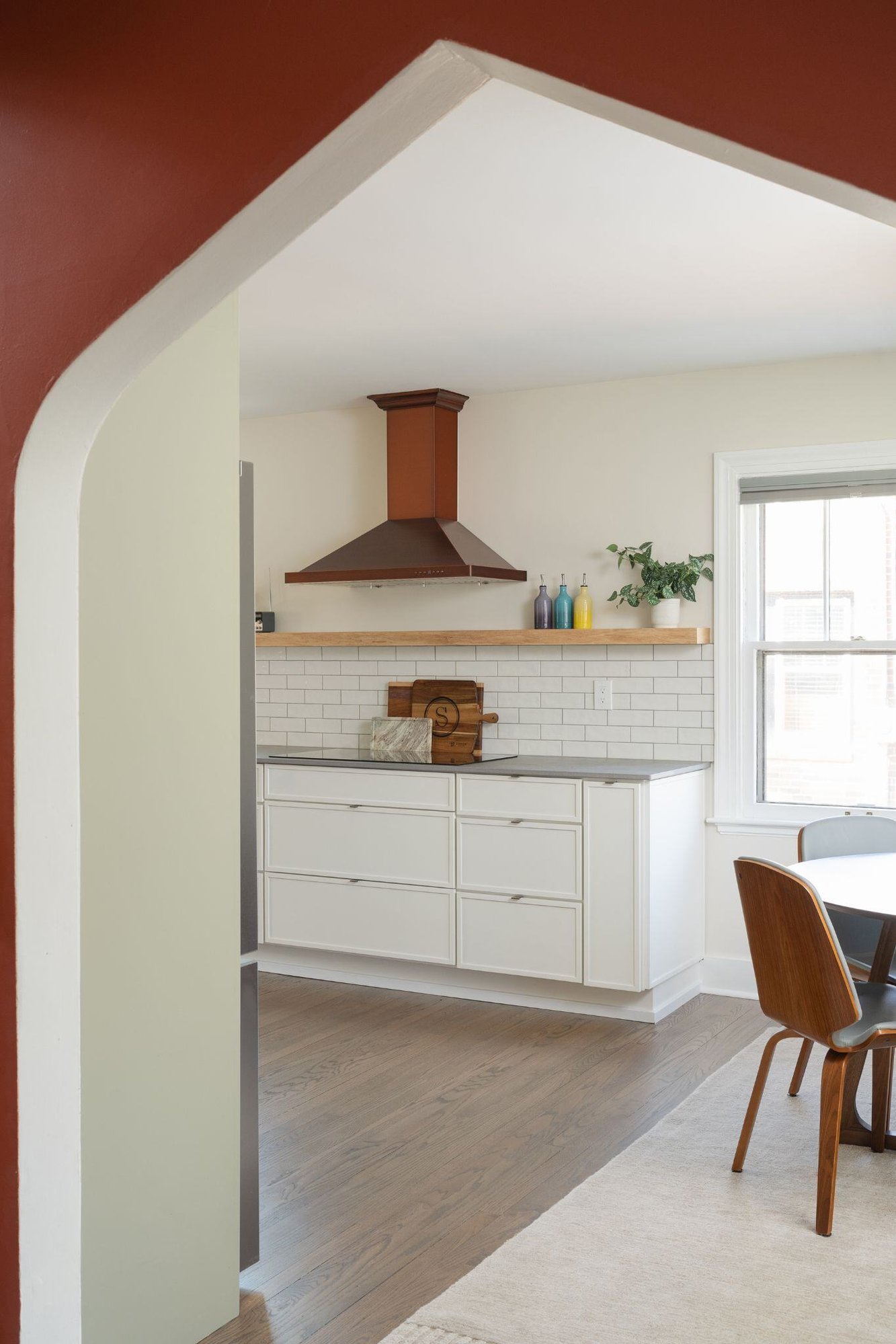 arched kitchen doorway in a remodeled kitchen with white cabinets and dark wood floors