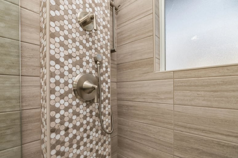Close up of shower with wood tile and wood and white circle accents