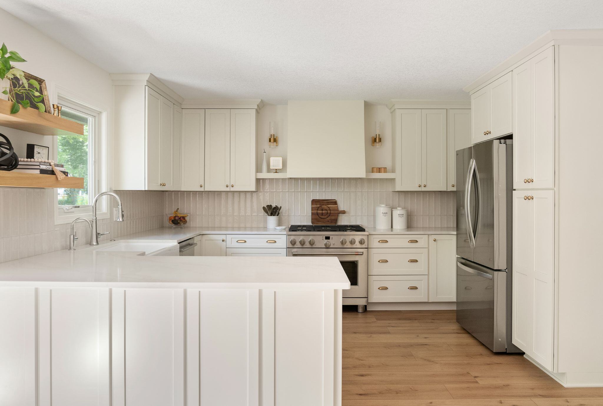 White kitchen remodel with stainless steel appliances, open shelving, and light wood floor