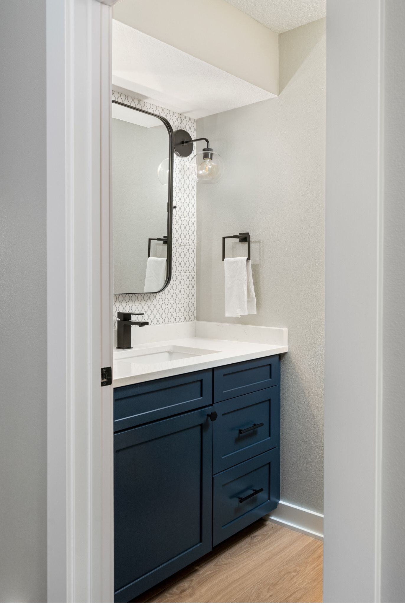 blue cabinets in a remodeled bathroom with white counter and black hardware