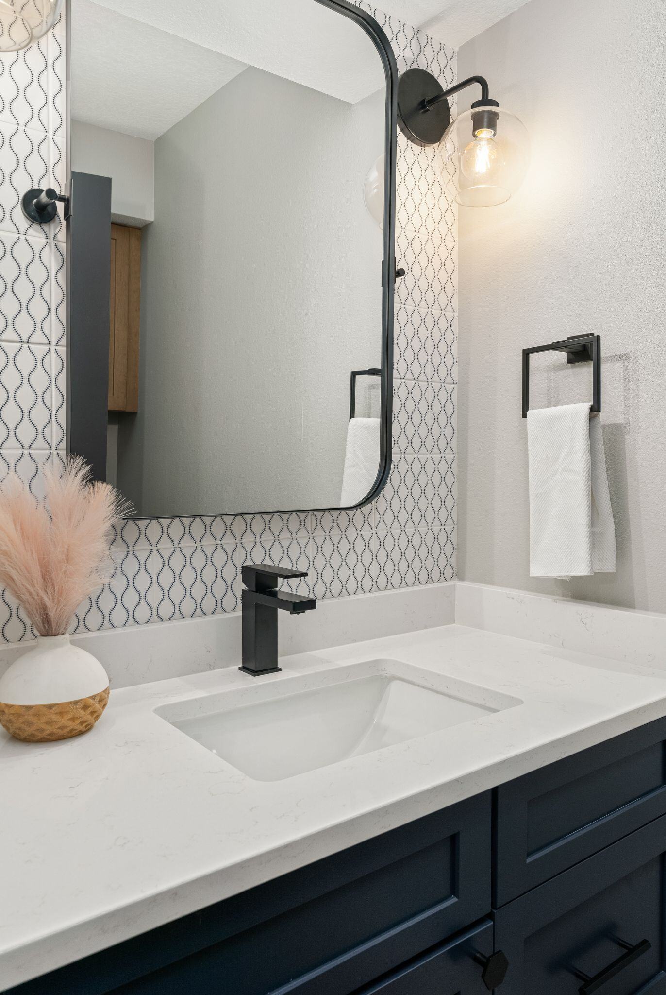 Remodeled bathroom in Des Moines with white counter and unique backsplash