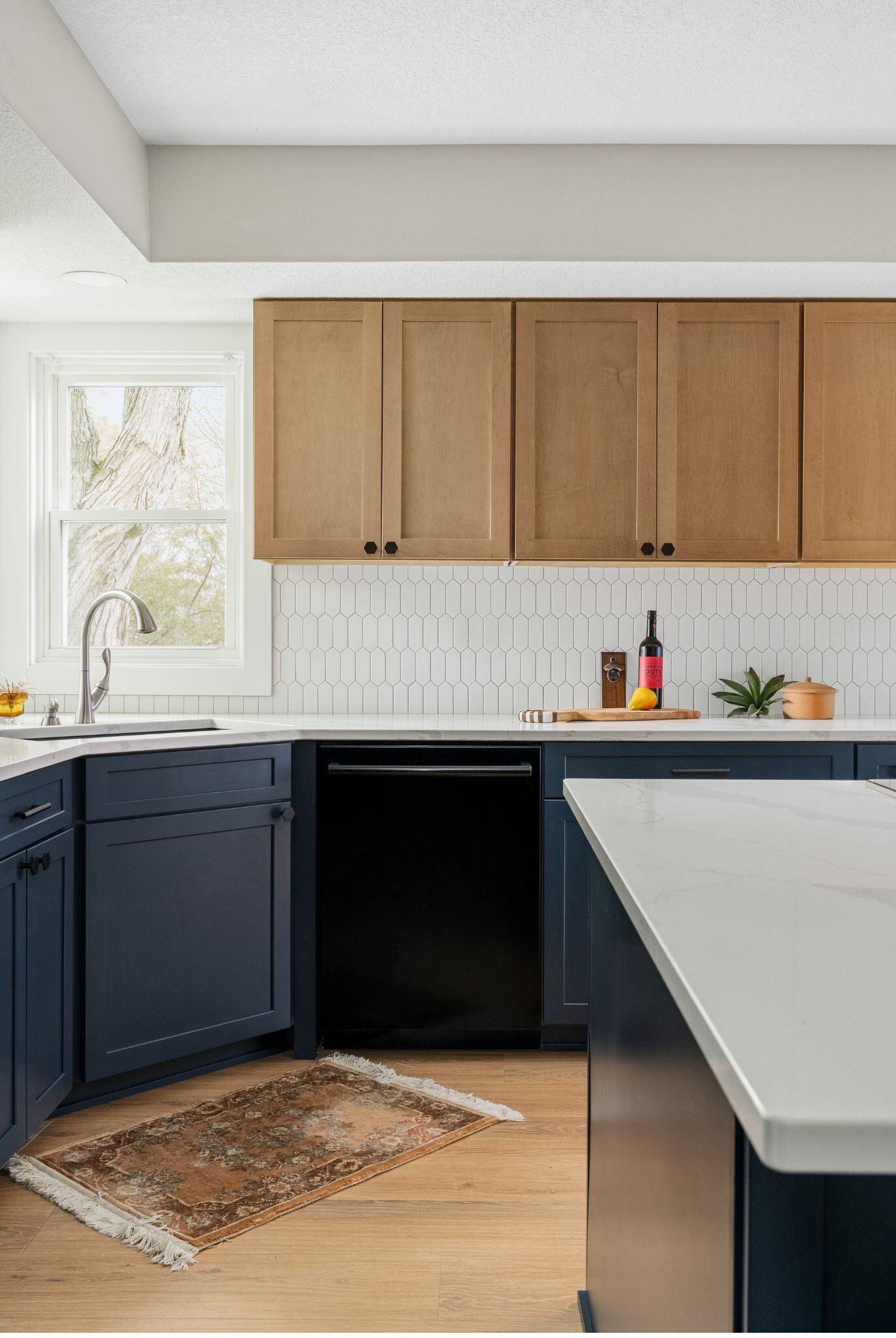 Kitchen remodel in Des Moines with dark blue cabinets, white counters and backsplash, and light wood flooring