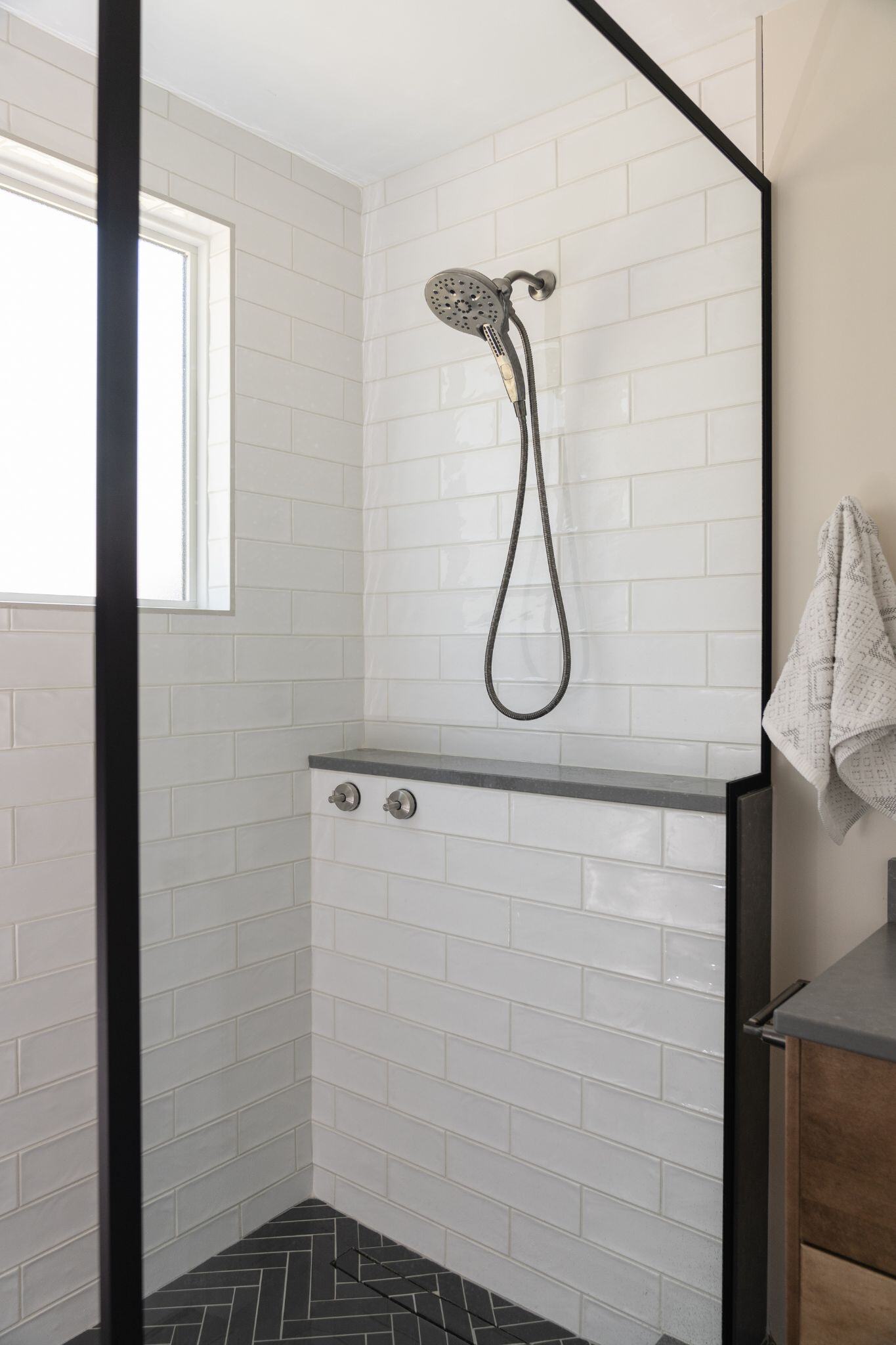 Modern white tile shower renovation with matte black herringbone floor