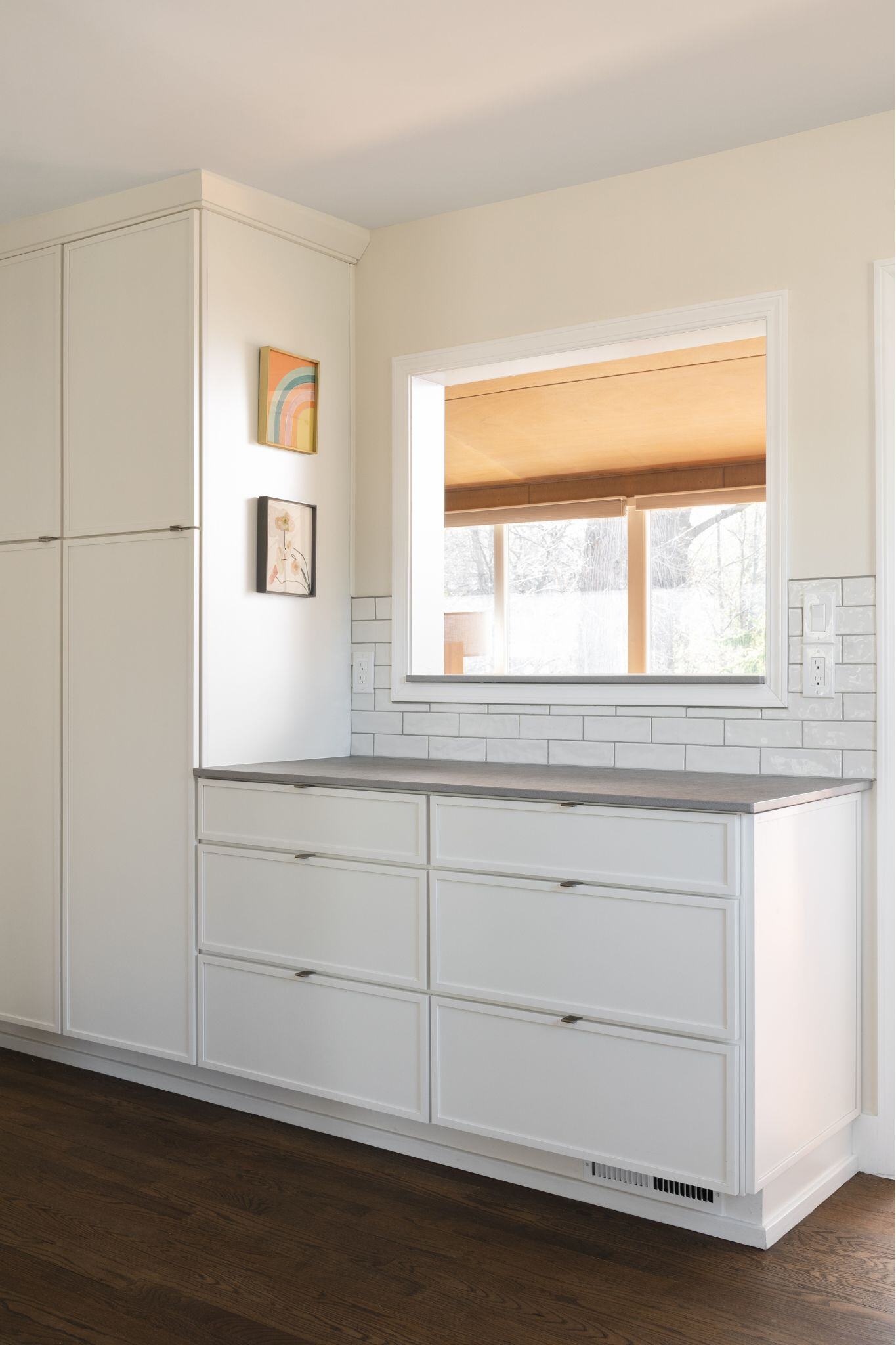 white kitchen cabinets and gray countertop underneath an interior window in a home remodel in des moines iowa