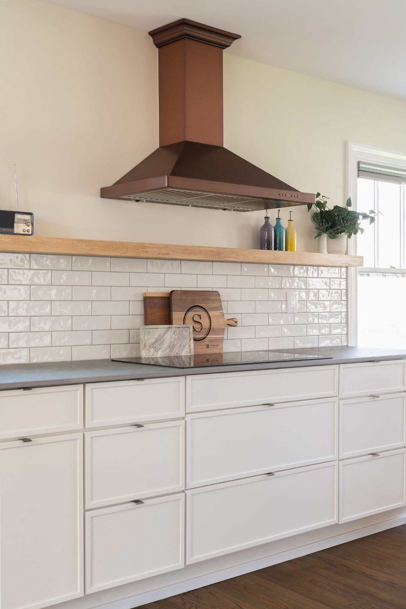 Copper oven vent hood in a modern, white kitchen remodel in des moines iowa