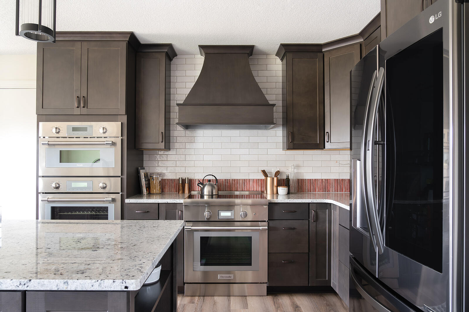 Luxury kitchen remodel in Urbandale, Iowa with custom dark cabinetry and matching vent hood.