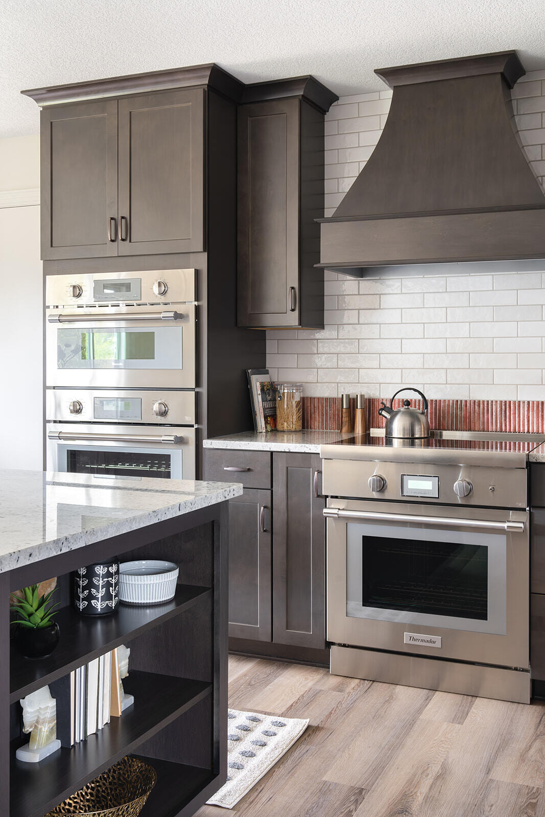 Kitchen Remodel with large kitchen island with open shelving, stainless steel double oven and microwave, and dark cabinets