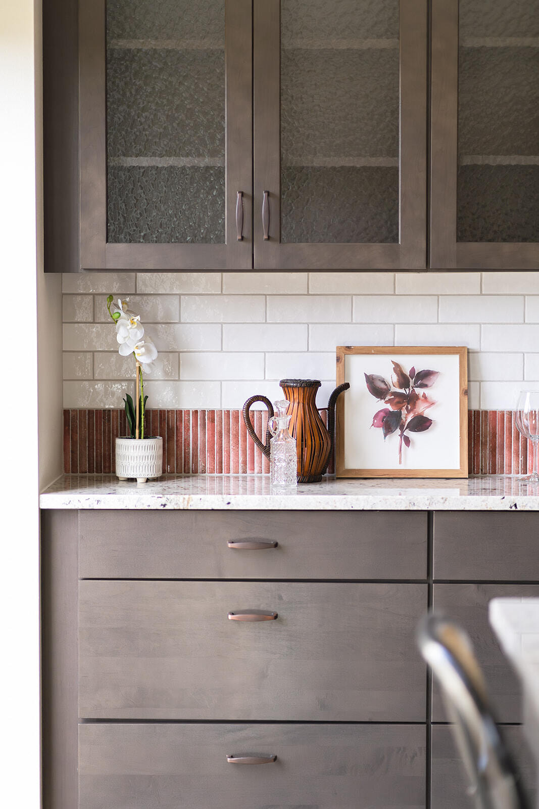 Custom kitchen cabinets with dark wood stain and white kitchen countertops and white subway tile backsplash with vertical orange tile accents