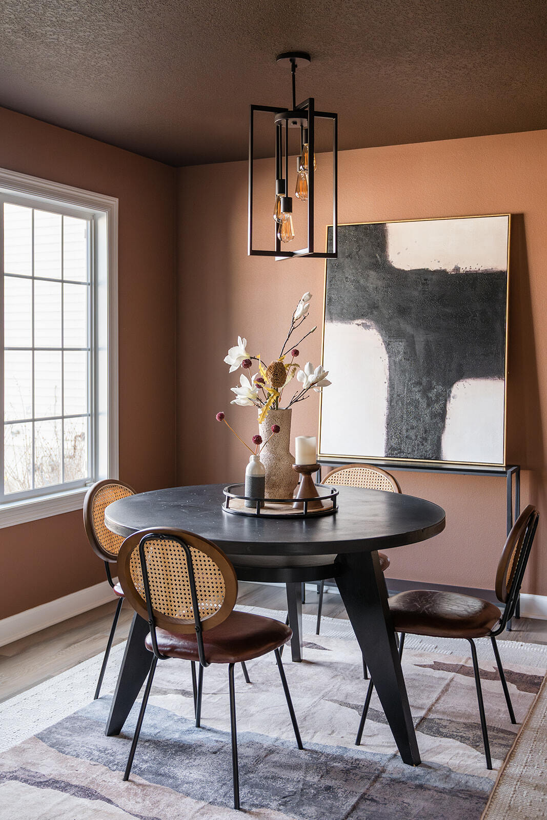 Remodeled dining room in urbandale, Iowa with custom lighting fixture, clay colored walls, and dark circular dining table