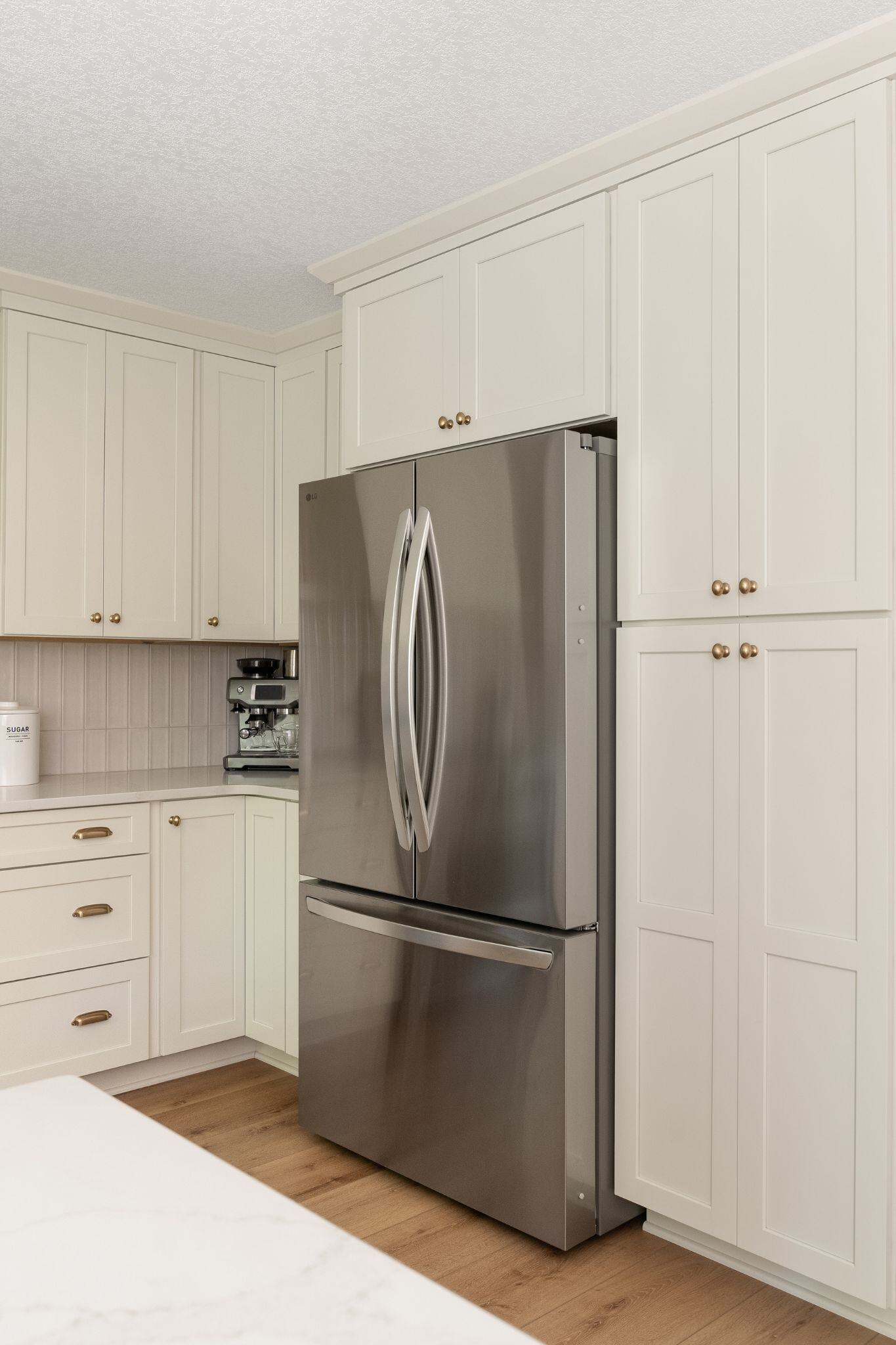 Kitchen remodel with white cabinets and a stainless steel fridge