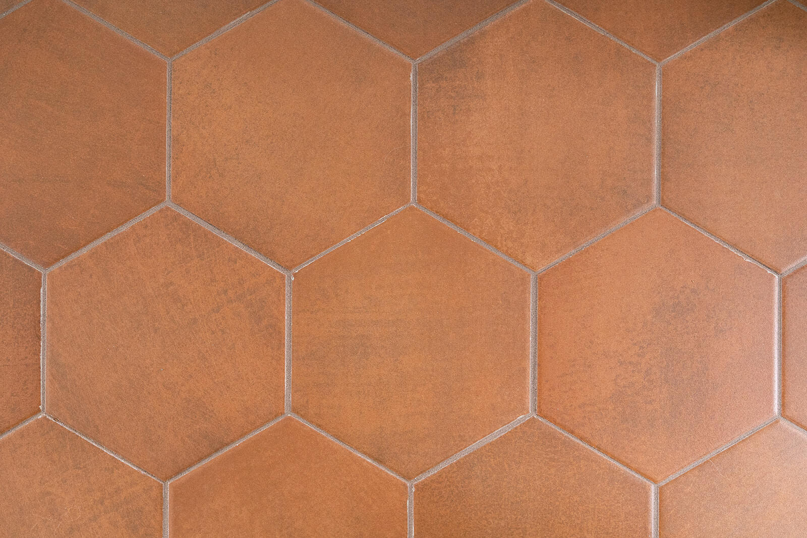 Close up image of hexagon shaped kitchen floor tiles in brushed red clay color