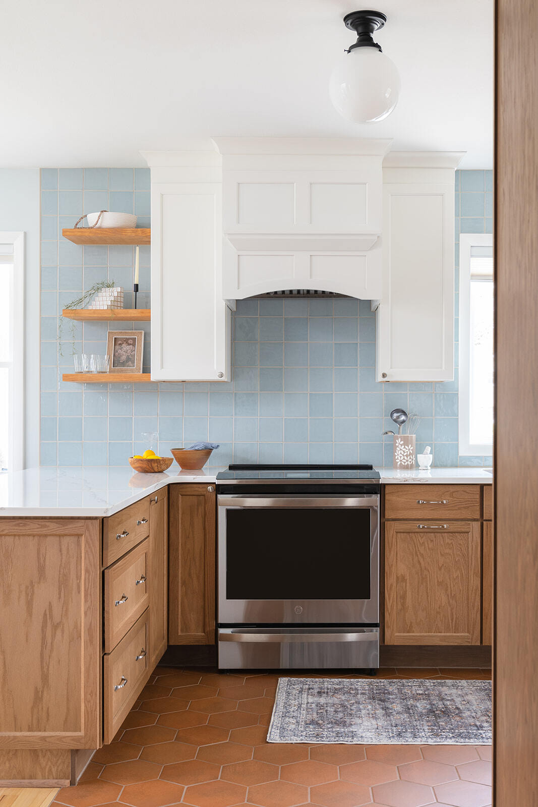 Kitchen Remodel in Des Moines featuring hexagonal red clay floor tile, stainless steel oven, wooden lower cabinets and white upper cabinets