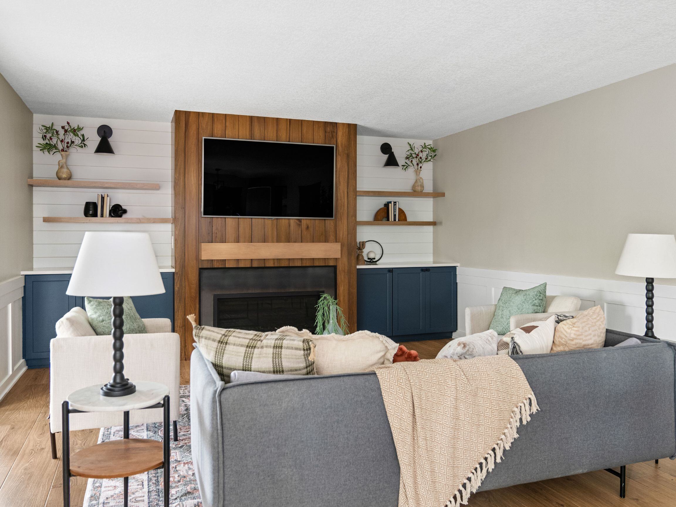 Remodeled living area with wooden paneled fireplace and blue shelving on each side